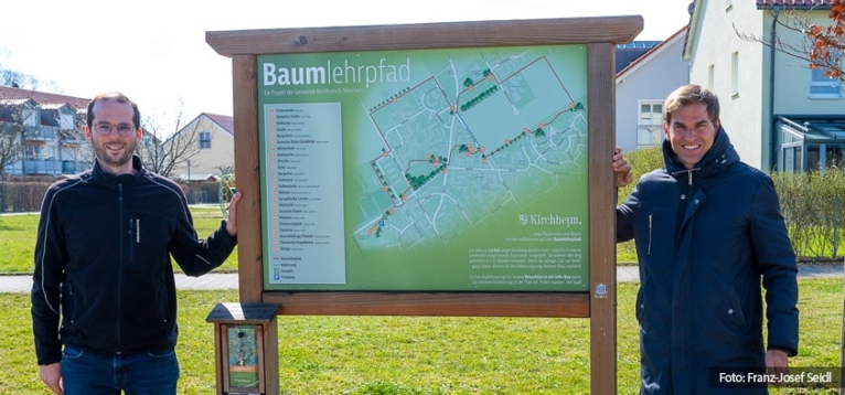 Foto: Erster Bürgermeister Maximilian Böltl und Umweltsamtleiter Robert Maier neben der Infotafel für den Baumlehrpfad.