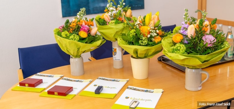 Foto: Blumensträuße, Ehrennadeln- und medaillien für die ehemaligen Gemeinderatsmitglieder.
